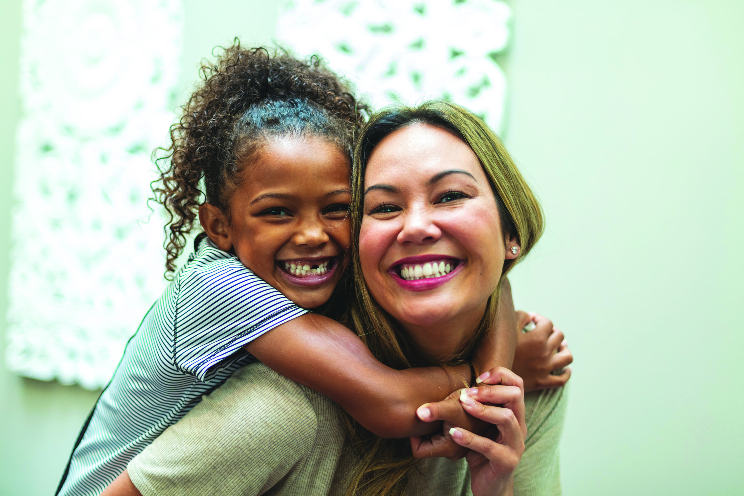 Asian Mother with daughter of mixed Chinese and African American ethnicity at home indoors posing for portraits smiling and being silly | Voices Children